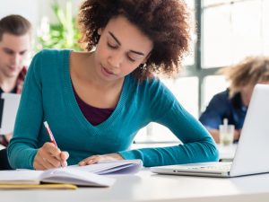 Jeune fille qui étudie entourée d'autres étudiant·es. Image représentant les sciences humaines, administration.