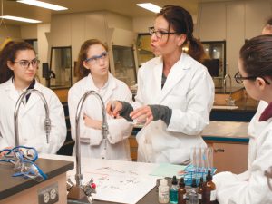 Enseignante donnant un cours dans un laboratoire entourée d'étudiant·es.