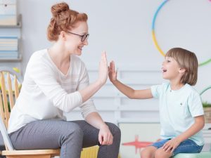une femme et un enfant se tappant dans la main. Image représentant les sciences humaines, psychologie et interactions sociales.