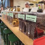 Comptoir avec les bacs de denrées en vrac accompagné de quelques étudiantes et étudiants.