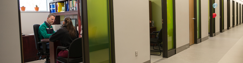 Vu d'un corridor du Collège où l'on voit un API aidant un étudiant.