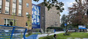 Façade de la bâtisse sur laquelle on admire une géante murale avec une trame art déco avec différentes teinte de bleu.