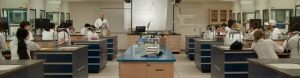Étudiants dans une classe laboratoire. Un prof à l'avant de la classe leur enseigne la matière.